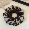Detail of houndstooth knit hair scrunchie with golden BE HAPPY metal charm and soft texture - Brown & White Houndstooth / Brown
