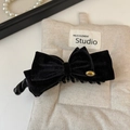 Detalle del elegante pasador de terciopelo negro con emblema dorado sobre fondo de tela - Negro