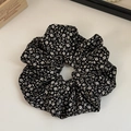 Détail d'un chouchou floral en mousseline noire avec de délicates fleurs jaunes et blanches - Moucheté Noir et Blanc