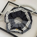 Detailed macro view of lace hair scrunchie with polka dots and handmade metal tag - Black and Gray