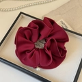 Close-up of burgundy satin scrunchie with edge stitching and pearl pendant detail - Red