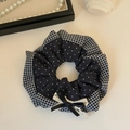 Detailansicht eines dunkelblauen Gingham-Haargummis mit Spitzenschleife und Polka-Dot-Muster - Grau