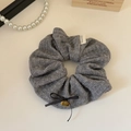 Detail of grey knitted scrunchie with a Hand Made label and golden cherry charm - Gray