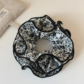 Detailaufnahme von Vintage Blumen Haargummi mit schwarzer Paspel und weichem Stoffmuster - Cremeweiß Blumiges Plissee Modell
