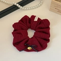 Close-up of knit fabric scrunchie with bow and gold cherry pendant on table - Burgundy
