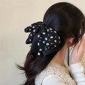 Dettaglio di fiocco in rete a fiori con pendenti in perla sui capelli della modella - Nero Stampato