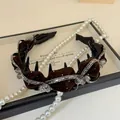 Dettaglio di un cerchietto in velluto marrone con strass e perline di cristallo - Marrone
