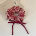 Dettaglio dell'elastico a scacchi rossi con fiocco in raso e ciondolo a perla fine - Nappina a Fiocco Rosso
