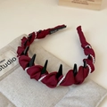 Detail eines burgunderroten Satin Stirnbands mit Perlen, Spikes und Hand Made Etikett - Perlenumwickelter Stil