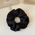 Dettaglio di un elastico per capelli in raso nero con volant e perle grigie - Stile Perla Nera