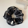 Dettaglio di scrunchie a scacchi con ricamo floreale rosa ed etichetta Hand Made - Nero