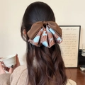 Elegante strik haarclip met bruin satijn en bloemmotief gedragen door een model - Bruin
