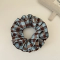 Detalle de scrunchie a cuadros azul y marrón mostrando textura de tela y pliegues - Azul Doble Capa