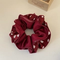 Detail of burgundy satin polka dot scrunchie with soft ruffled texture and silky finish - Red