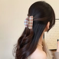 Detalle de una pinza para el pelo a cuadros grande que sujeta un moño informal de mujer - Pinza Semicírculo a Cuadros