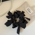 Detailed view of black polka dot mesh scrunchie with bows on a linen storage bag - Black
