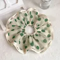 Detail showing elegant chiffon scrunchie with green polka dots and CHANGE letter ribbon - Beige