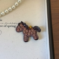 Dettaglio del fermaglio per capelli a forma di pony con strass colorati su bianco - Viola