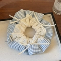 Dettaglio dell'elastico a quadretti blu con bordo in pizzo bianco e fiocchi di perle - Righe Blu Pizzo