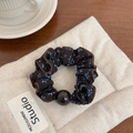 Close-up of floral scrunchie in dark brown fabric with blue flowers and bead on linen bag - Gray