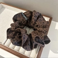 Dettaglio di uno scrunchie leopardato con etichetta Fashion su vassoio bianco - Leopardo Caffè Scuro