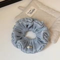 Detail showing blue pleated scrunchie with a white pearl and a gold wings logo tag - Blue