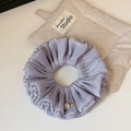 Close-up of lilac satin scrunchie with pearl and Wings metal pendant detail - Purple