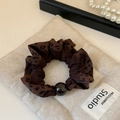 Detailweergave van luipaardprint scrunchie met bruine kraal op beige linnen textiel - Donker Koffie Luipaard Scrunchie