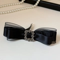 Macro-detail van een zwarte satijnen strik met luxe vierkante strass-gesp - Zwarte veerclip