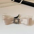 Detail van champagne haarklem met strass gesp en lagen van satijn en transparant organza - Witte veerklem