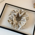 Detailweergave van bloemen scrunchie met geel bloempatroon en fijne afwerking - Beige Bloemenprint