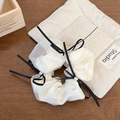 Dettaglio scrunchie in organza bianca con fiocchi neri e perle su base in legno - Rete Bianca