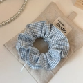 Dettaglio di un elastico per capelli a scacchi blu con volant su un sacchetto di tessuto - Quadri Blu