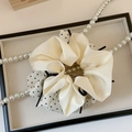 Détail d'un chouchou en satin à pois double couche posé sur un plateau avec perles - Kaki et Blanc