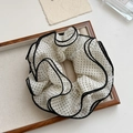 Détail d'un chouchou vintage à pois avec bordure à volants multicouches sur un plateau - Beige à Pois