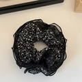 Detailaufnahme des schwarzen Haargummis mit Blumenmuster und mehrschichtiger Netzoptik - Schwarz