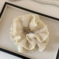 Detalle de un coletero gigante plisado crema con bordes de volantes y textura de seda - Blanco Roto