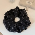 Detail shot of oversized mesh scrunchie with purple floral pattern on white surface - Black-Large