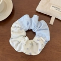 Detail of checkered and floral patchwork scrunchie on a rustic wooden surface - Scrunchie / Blue Plaid