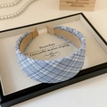 Detailopname van een brede blauwe geruite haarband op een display met parelketting - Brede Hoofdband / Blauw