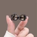 Detailed macro view of a vintage bow hair clip with dark grey faceted crystal stones - Black Duckbill Clip