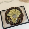 Détail d'un chouchou à froufrous marron et crème avec étiquette Original distinctive - Style à Volants Jaune et Marron
