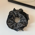 Detailed close-up of floral mesh scrunchie fabric with intricate pleated textures - Black