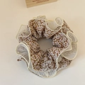 Detail of floral scrunchie with white organza overlay on a cream textile background - Beige
