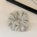 Dettaglio di un elastico per capelli in rete bianca a pois neri su fondo bianco - Beige Rete Pois