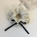 Dettaglio di elastico color crema a pois con fiocco nero e ciondolo di perla elegante - Beige a Pois