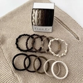 Detail view of twist texture hair ties in earthy tones on a beige knit background - Wrapped Style