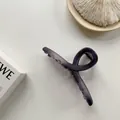 Vista dettagliata della molletta opaca viola scuro con design geometrico su tavolo bianco - Viola