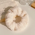 Close-up of soft beige plush scrunchie with fluffy lamb wool texture on wooden tray - Curly Faux Fur