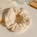 Detailansicht eines cremefarbenen Plüsch-Haargummis mit gestreifter Textur - Gestrickter Stil